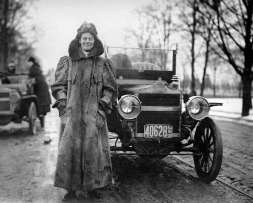 Una mujer con un abrigo mostrando bienestar junto a un coche.