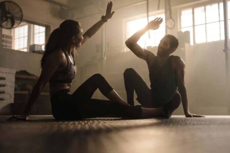 A couple practising fitness and wellness through yoga in a gym.