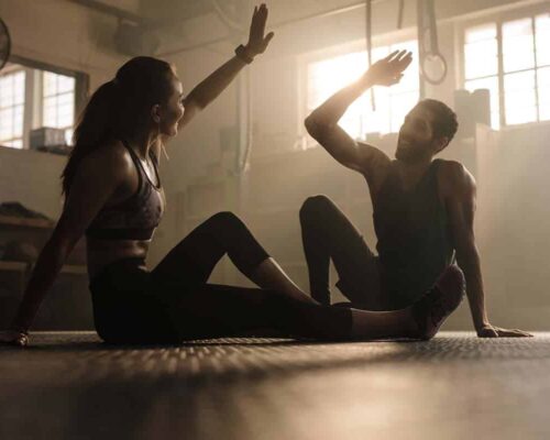 Una pareja practicando fitness y bienestar a través del yoga en un gimnasio.