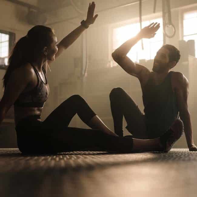 Una pareja practicando fitness y bienestar a través del yoga en un gimnasio.