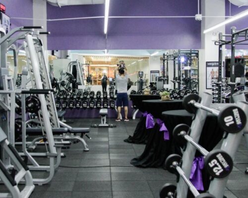 Un gimnasio en traspaso con una gran cantidad de equipos y paredes moradas.