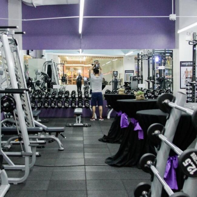 A gymnasium for lease with a large amount of equipment and purple walls.