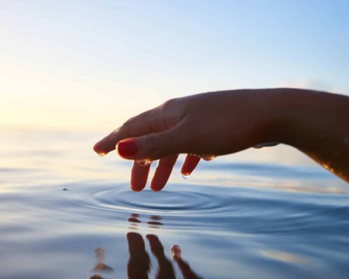 person about to touch the calm water